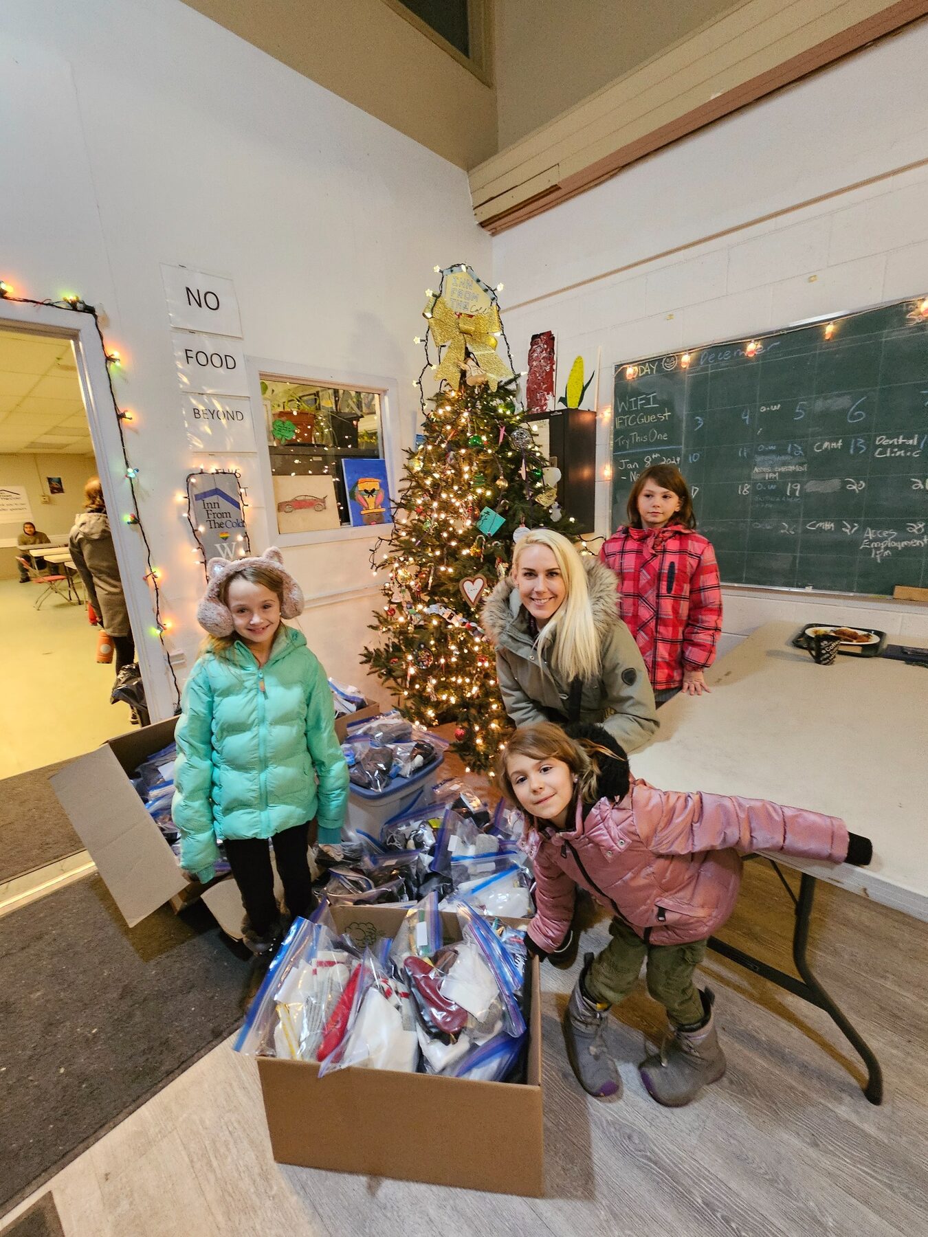 Jennifer and three children delivering care packages at a homeless shelter