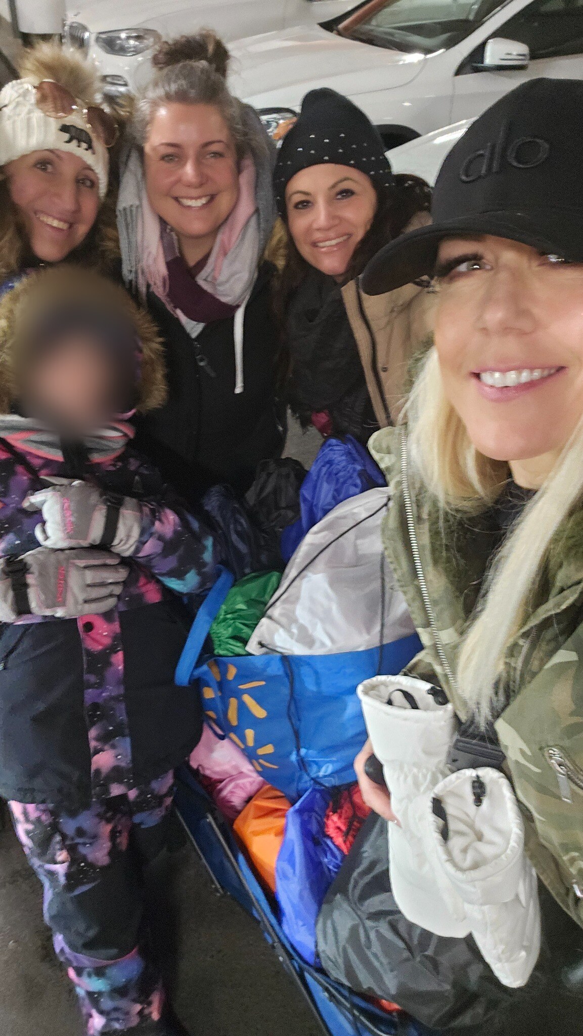 Four adult volunteers and one child preparing for winter outreach; the child’s face is obscured for privacy